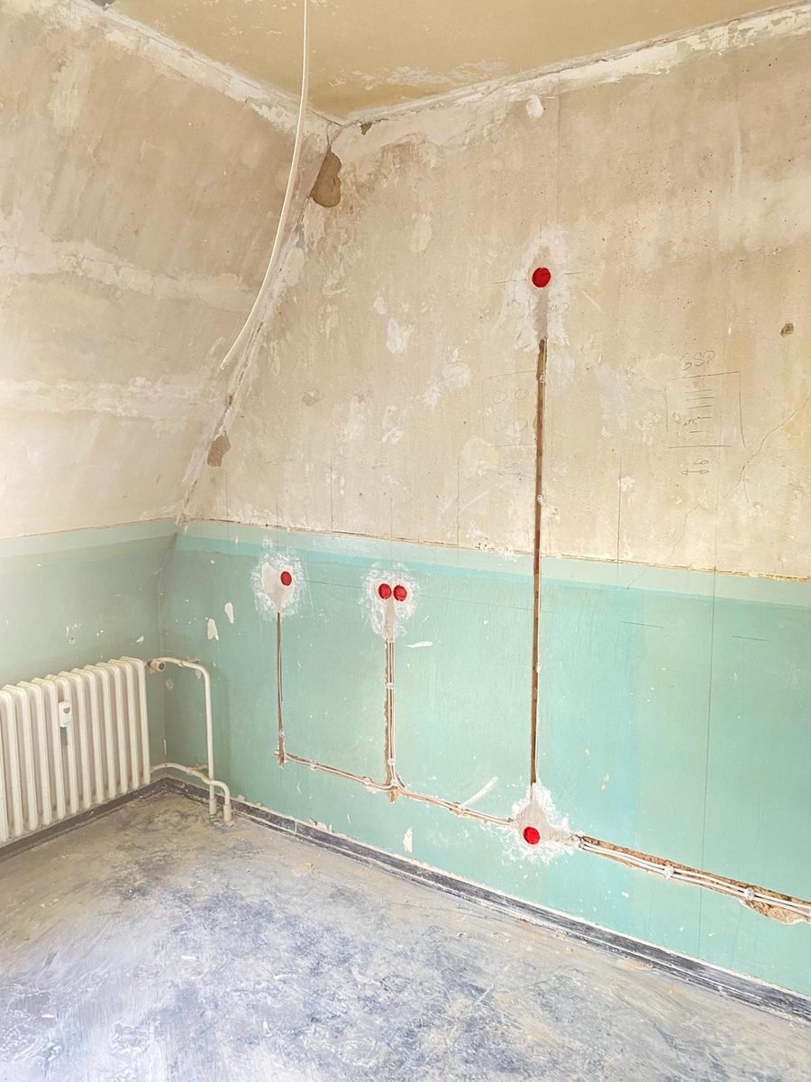 Geschlitzte Wand mit verlegten Leitungen und Dosen bei einer Elektroinstallation im Altbau